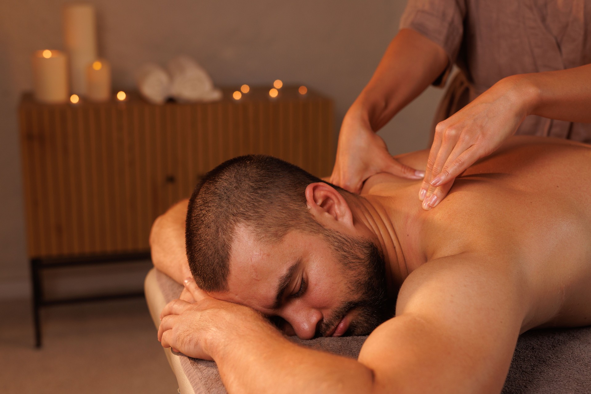 Close up of female massage therapist hands giving wellness therapeutic relaxing massage to man