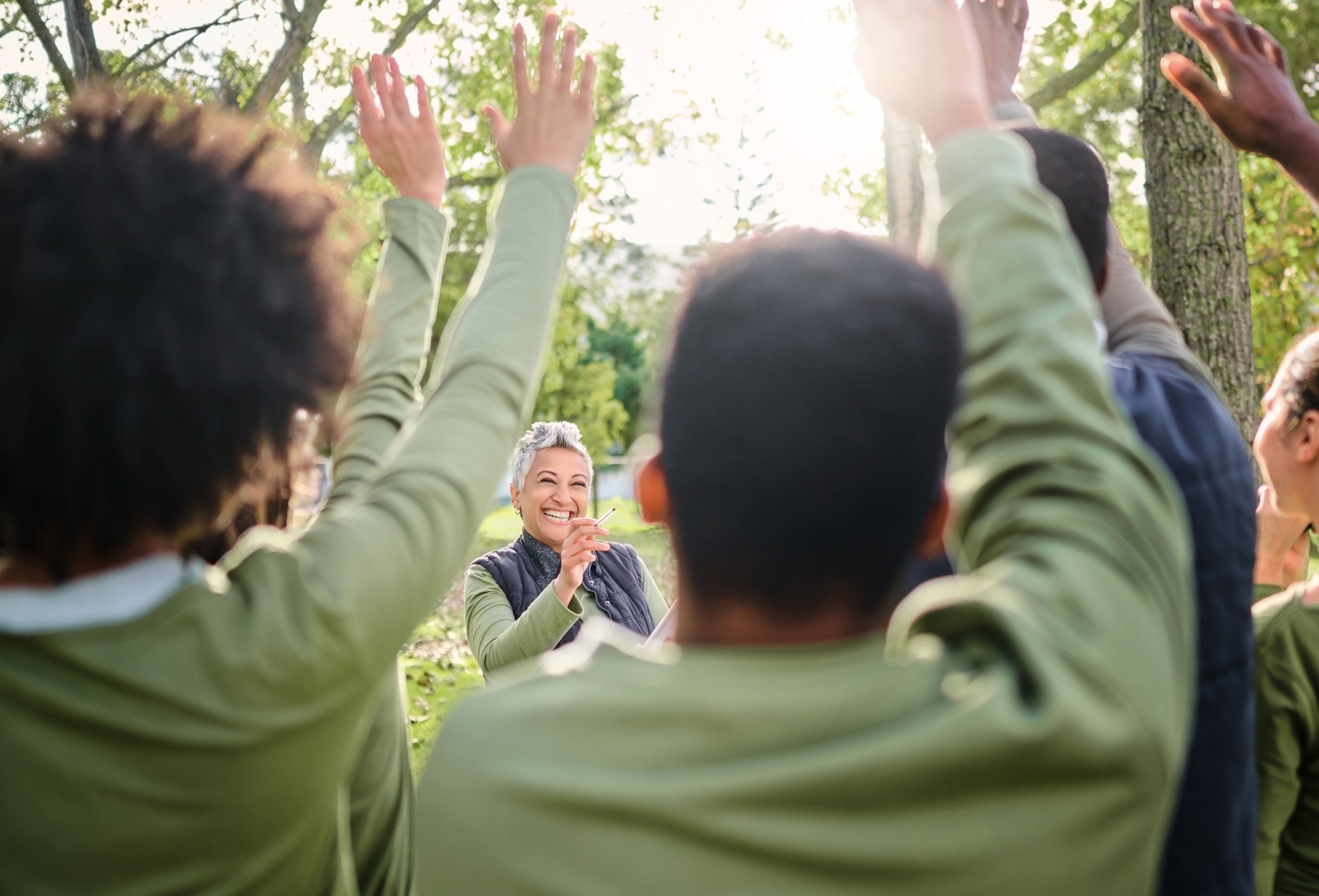 Volunteer, cleaning and group with vote for a woman in a park for the community environment. Teamwork, happy and people with questions for a senior leader during a nature cleanup for sustainability